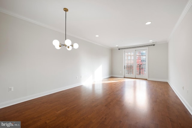 spare room with ornamental molding, wood-type flooring, and a chandelier