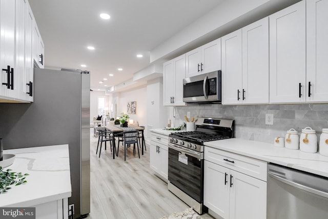 kitchen with white cabinets, stainless steel appliances, and light wood-type flooring