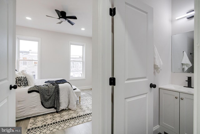 bedroom featuring sink, light wood-type flooring, and ceiling fan