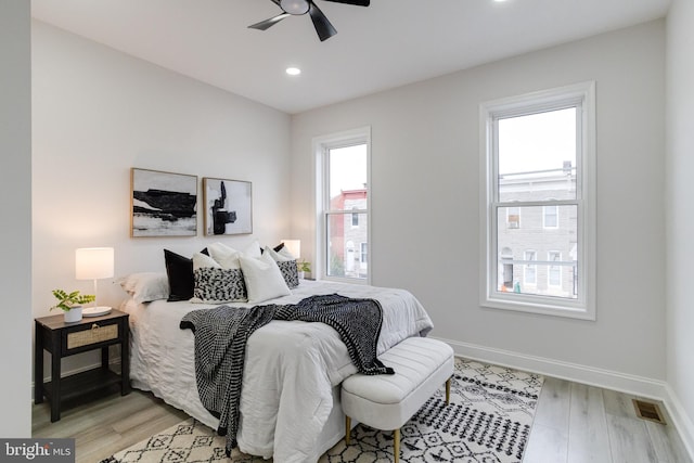 bedroom featuring ceiling fan, multiple windows, and light wood-type flooring