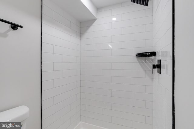 bathroom featuring a tile shower and toilet