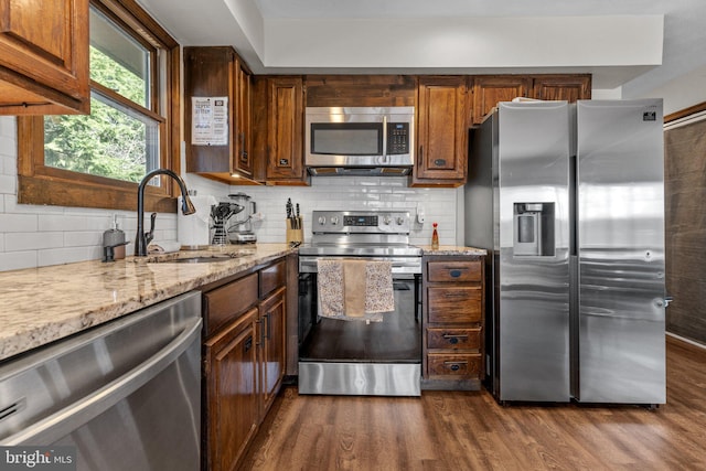 kitchen with light stone countertops, sink, appliances with stainless steel finishes, dark hardwood / wood-style flooring, and decorative backsplash