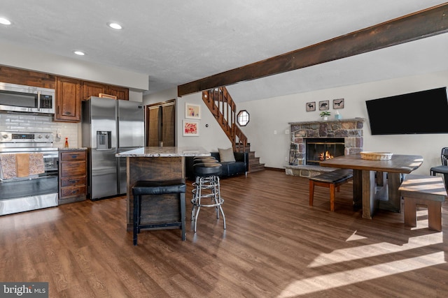 kitchen featuring a kitchen island, light stone countertops, a kitchen bar, dark wood-type flooring, and stainless steel appliances