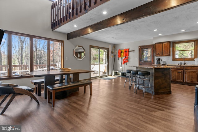 dining area featuring beamed ceiling, a textured ceiling, dark hardwood / wood-style floors, and sink