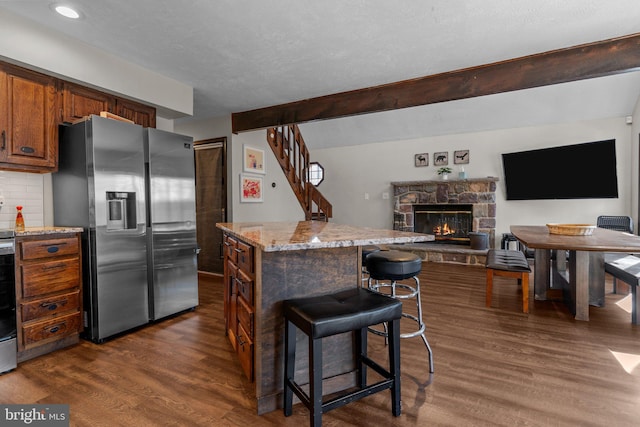 kitchen with dark hardwood / wood-style flooring, a breakfast bar, a center island, and stainless steel fridge with ice dispenser