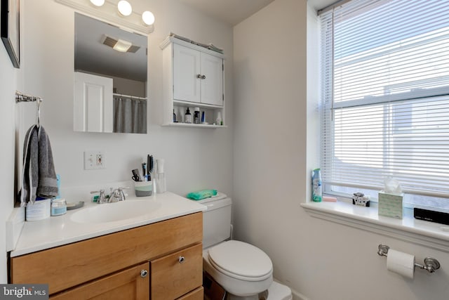 bathroom featuring toilet, vanity, and plenty of natural light