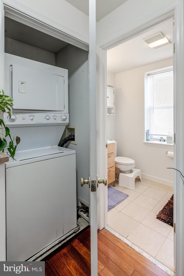 clothes washing area featuring stacked washing maching and dryer and light wood-type flooring