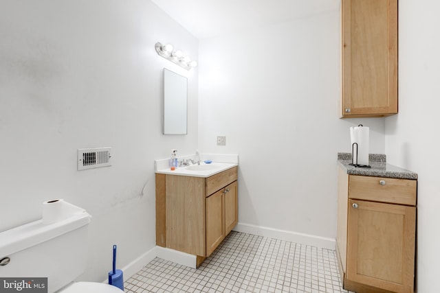 bathroom with toilet, vanity, and tile patterned floors