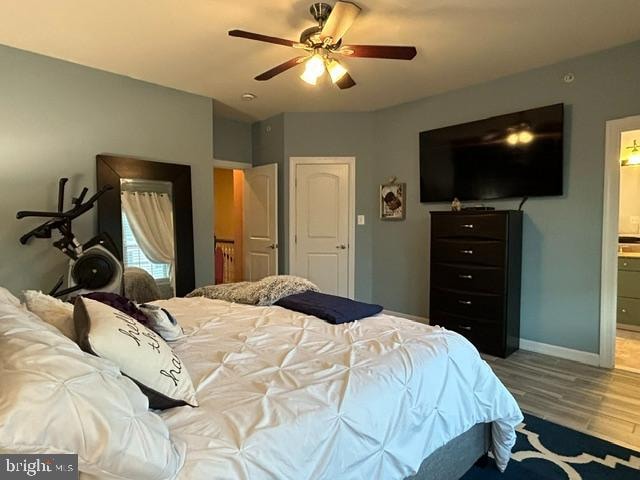 bedroom featuring ceiling fan, ensuite bathroom, and hardwood / wood-style flooring