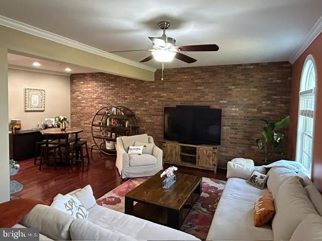 living room featuring ceiling fan, crown molding, brick wall, and dark wood-type flooring