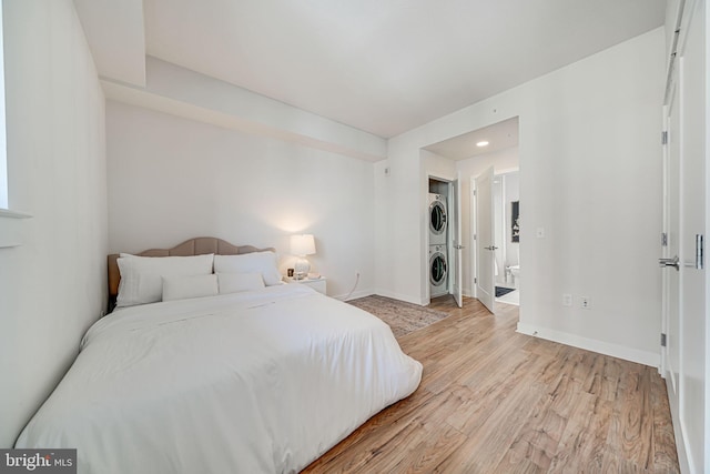 bedroom with a closet, stacked washer and dryer, and light wood-type flooring