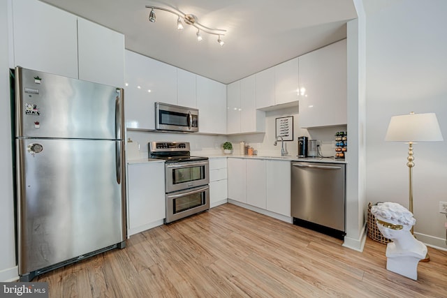 kitchen with white cabinetry, light hardwood / wood-style flooring, appliances with stainless steel finishes, and sink