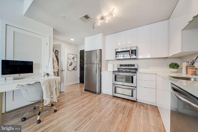 kitchen with light hardwood / wood-style flooring, white cabinetry, stainless steel appliances, and sink