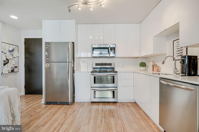 kitchen featuring white cabinetry, appliances with stainless steel finishes, light hardwood / wood-style flooring, and sink