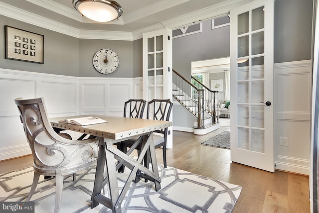 dining space featuring crown molding, light hardwood / wood-style flooring, and french doors