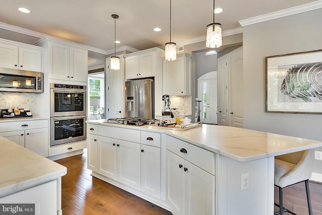 kitchen with appliances with stainless steel finishes, pendant lighting, and white cabinets