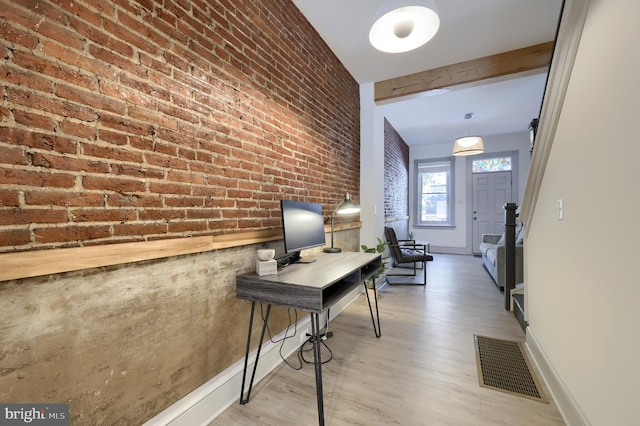 office with beam ceiling, light hardwood / wood-style flooring, and brick wall