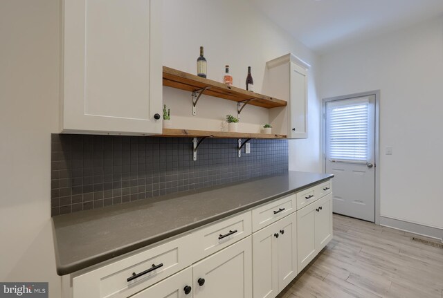 kitchen featuring tasteful backsplash, white cabinets, and light wood-type flooring