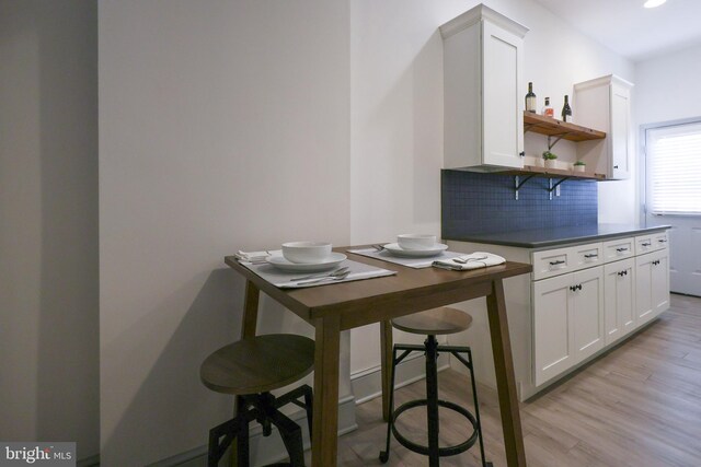 bar featuring tasteful backsplash, white cabinetry, and light hardwood / wood-style floors