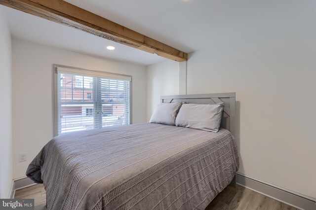 bedroom with beamed ceiling and hardwood / wood-style flooring