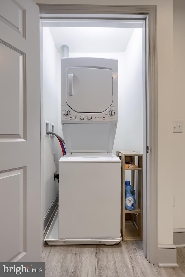 laundry room featuring light hardwood / wood-style flooring and stacked washing maching and dryer