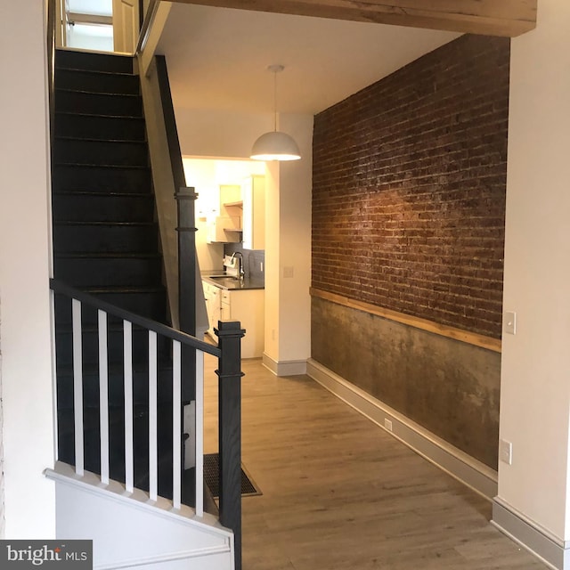 corridor featuring sink, brick wall, and wood-type flooring