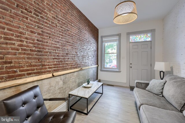 living room with light hardwood / wood-style floors and brick wall