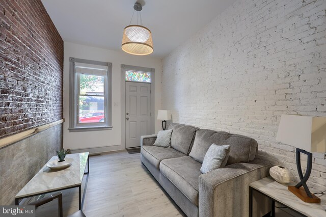 living room with light hardwood / wood-style flooring and brick wall