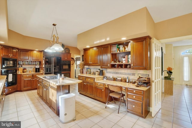 kitchen featuring black appliances, tasteful backsplash, a center island with sink, light tile patterned floors, and hanging light fixtures