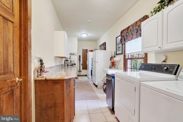 washroom with washing machine and clothes dryer, cabinets, and light tile patterned floors