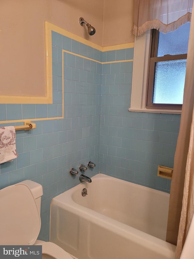 bathroom featuring tile walls, toilet, and shower / bathtub combination with curtain