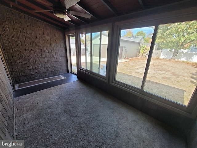 unfurnished sunroom featuring ceiling fan, lofted ceiling with beams, and wooden ceiling