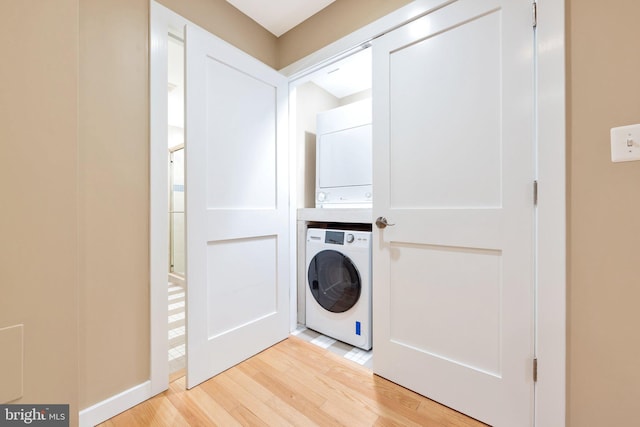 laundry room with stacked washer / dryer and light hardwood / wood-style flooring