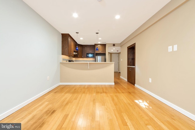 1415 Chapin St NW Unit Ll1, Washington, DC 20009 - kitchen featuring black microwave, stainless steel fridge, a peninsula, light countertops, and light wood-style flooring