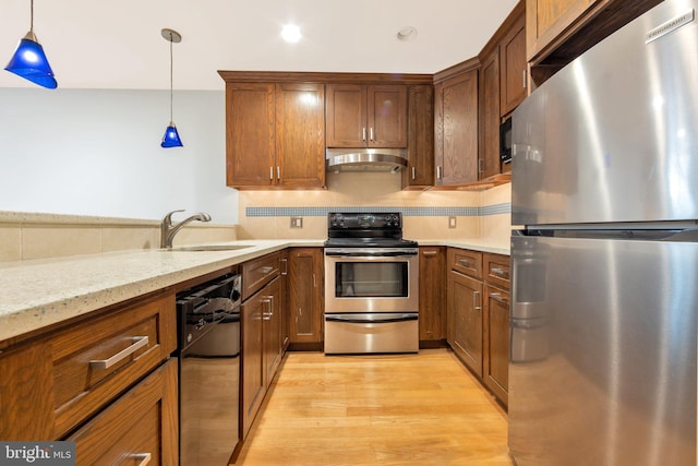 kitchen featuring hanging light fixtures, sink, appliances with stainless steel finishes, and light hardwood / wood-style flooring