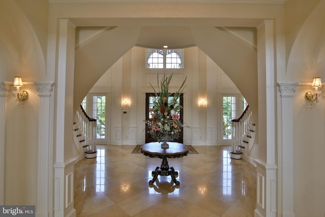 foyer entrance with a high ceiling, ornate columns, and crown molding