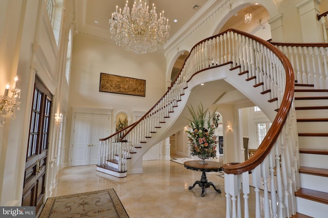 foyer featuring an inviting chandelier, crown molding, and a towering ceiling