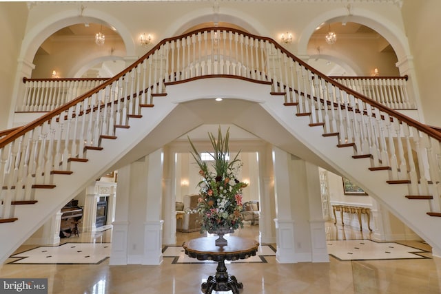 stairway featuring ornate columns, a towering ceiling, and crown molding