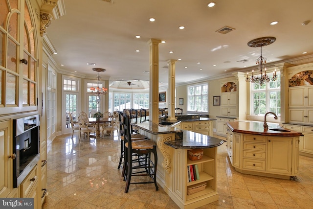 kitchen featuring hanging light fixtures, a healthy amount of sunlight, and a center island with sink