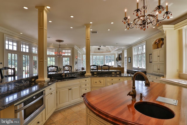 kitchen with cream cabinets, sink, decorative light fixtures, and decorative columns