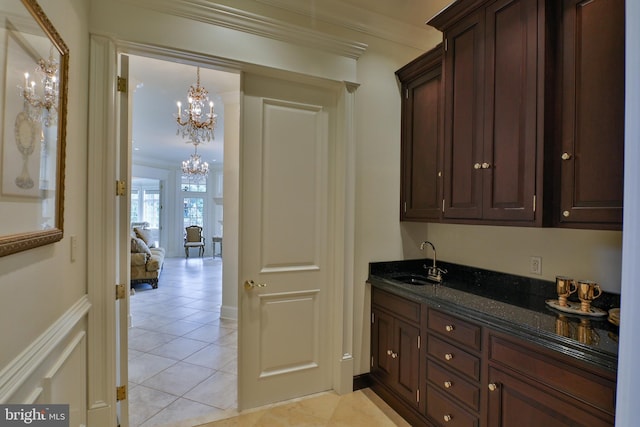 interior space featuring ornamental molding, dark brown cabinets, light tile patterned floors, sink, and dark stone countertops