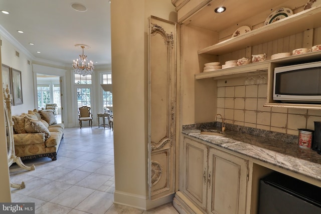 interior space featuring light tile patterned flooring, light stone counters, ornamental molding, an inviting chandelier, and decorative backsplash