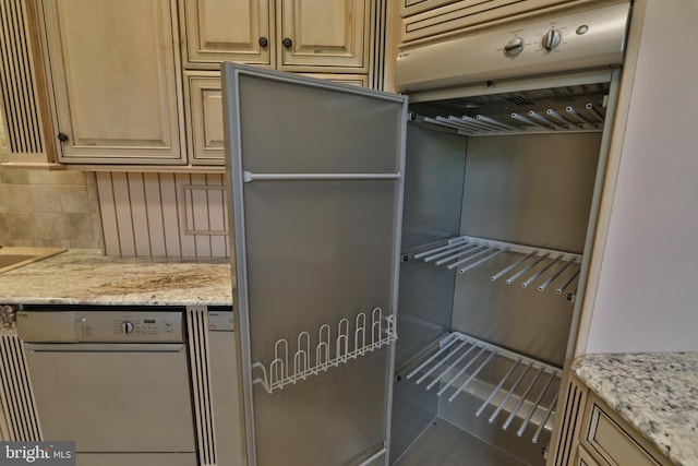 kitchen featuring tile patterned floors, backsplash, fridge, light stone countertops, and dishwashing machine