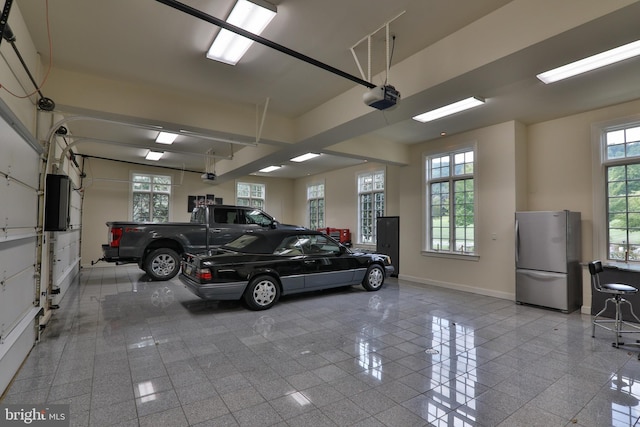 garage with a garage door opener and stainless steel fridge