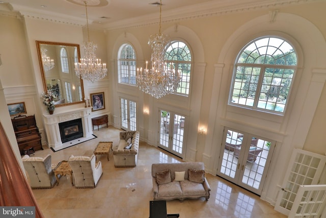 living room featuring french doors, a towering ceiling, a notable chandelier, and ornamental molding