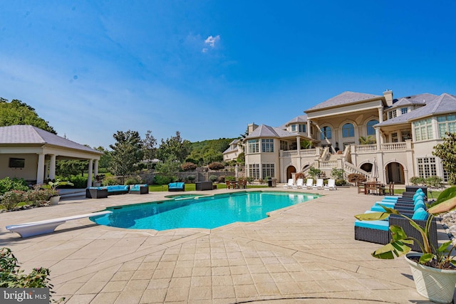 view of pool featuring an outdoor living space, a patio, and a diving board