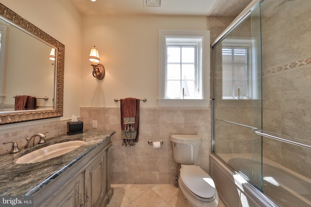 full bathroom with enclosed tub / shower combo, tile patterned flooring, toilet, and tile walls