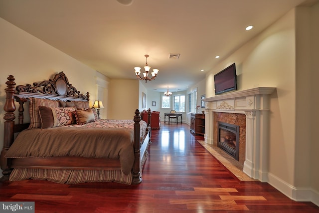 bedroom with a chandelier, dark hardwood / wood-style floors, and a fireplace