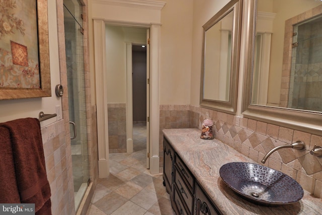 bathroom with tile walls, tile patterned flooring, vanity, crown molding, and a shower with shower door