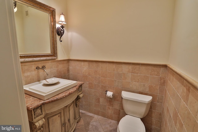 bathroom with vanity, tile patterned floors, toilet, and tile walls